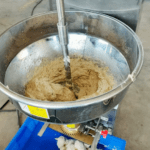 Vista superior de máquina formadora de bolas para carne de hamburguesa HAF-T40 con cuba de mezcla y masa cárnica en proceso